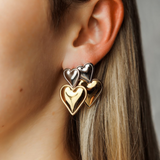 Close-up view of Giselle Earrings highlighting stacked heart detail in gold and silver.