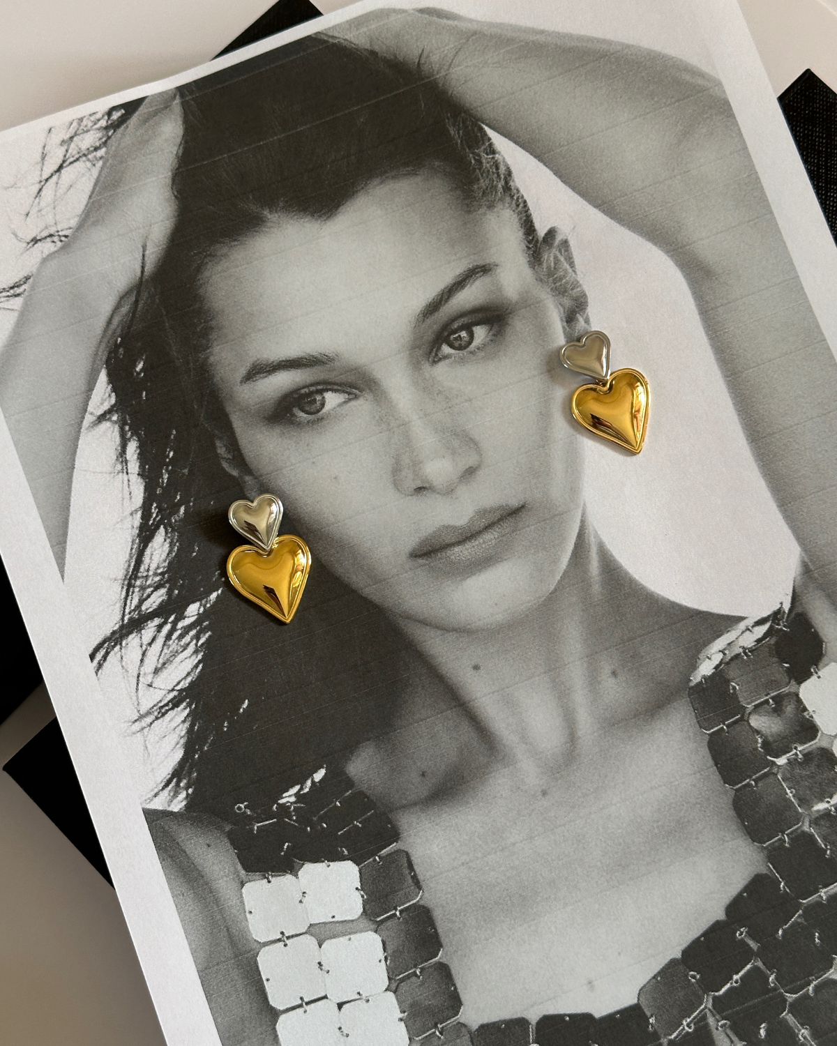 Front view of model wearing gold and silver Giselle heart drop earrings.