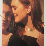 Ina Necklace worn alone on model’s neck with delicate gold chain and pearl.