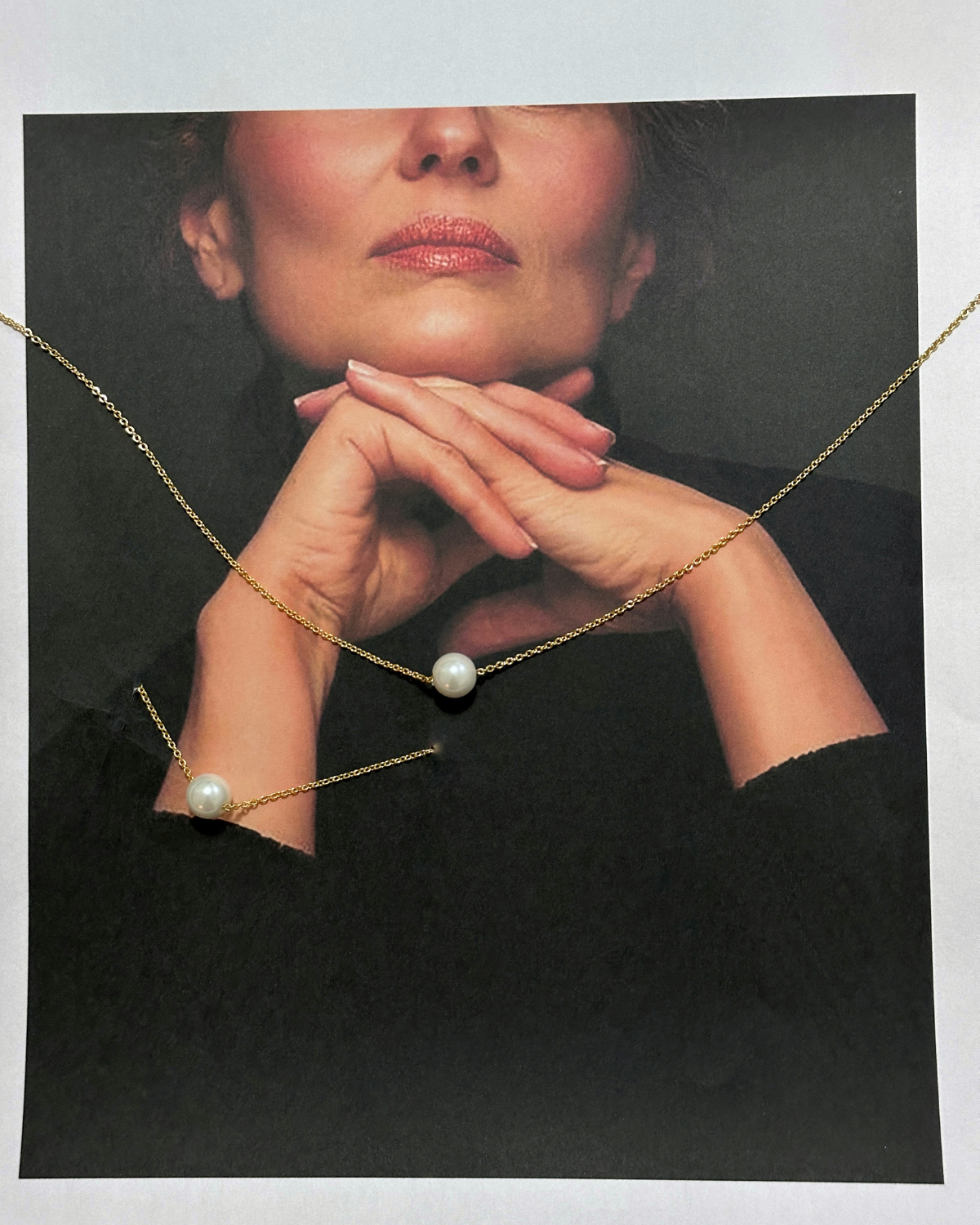 Model wearing Ina Necklace, closeup of pearl pendant on gold chain.