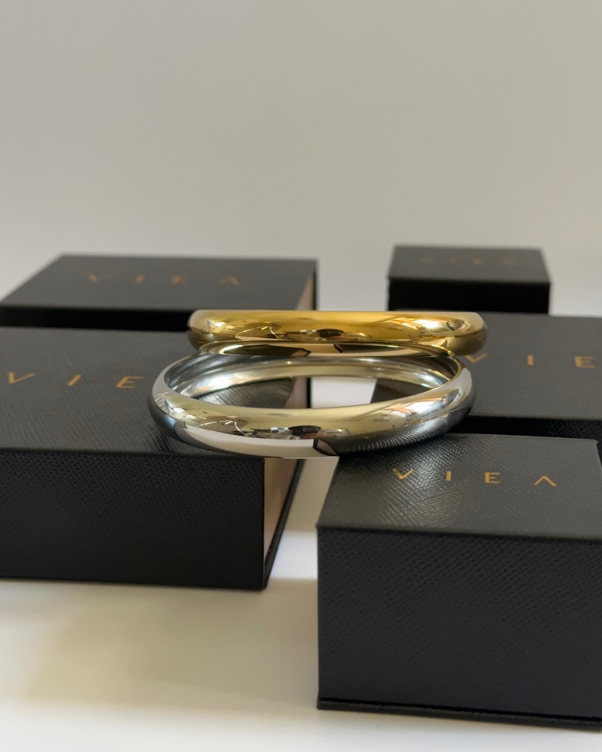Silver and gold Indie Cuffs stacked together atop VIEA Jewelry packaging.