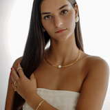 Half-body shot of Loreli Choker in a chic outfit, gold with pearl center.