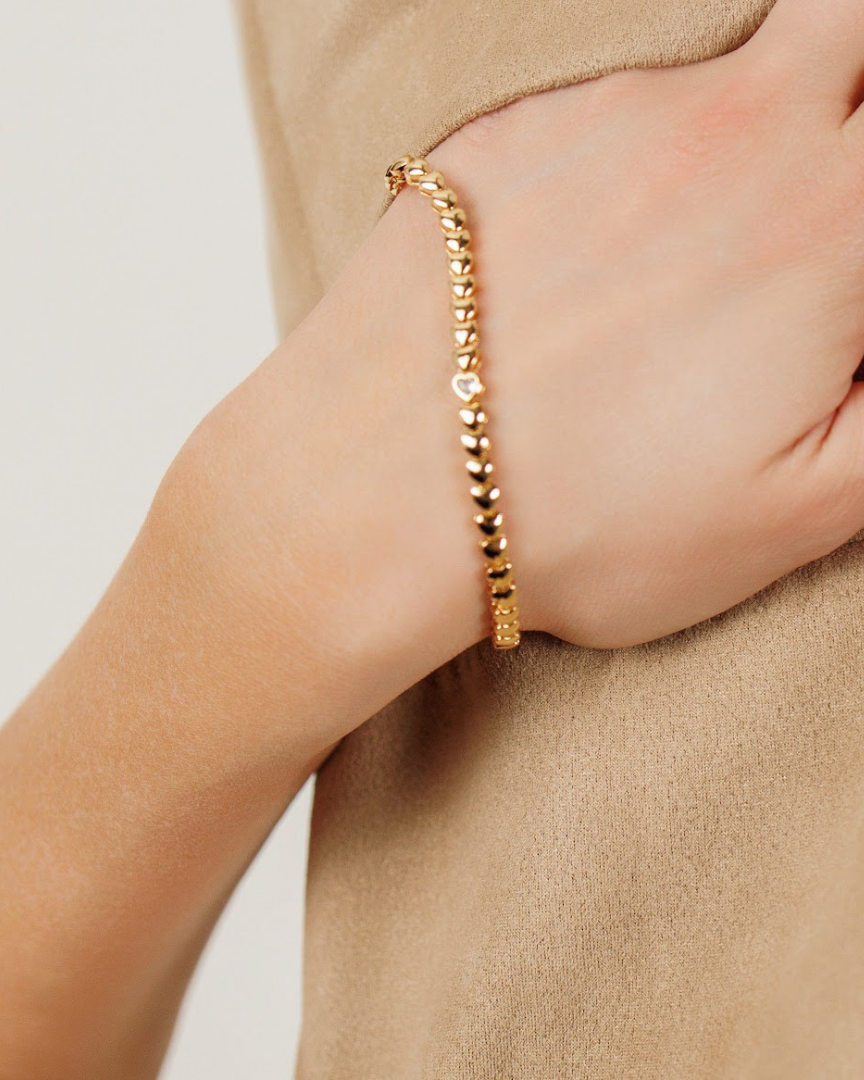 Close-up of Love Bracelet worn on wrist, highlighting its heart-shaped links and bold gold finish.