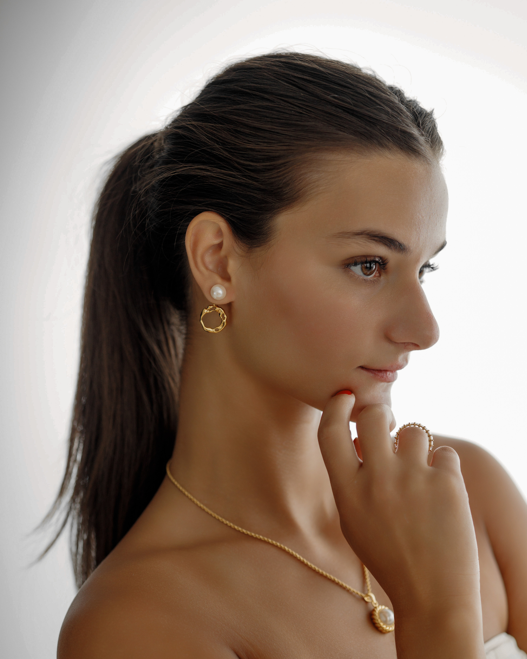 Model styling Maria Earrings with visible hoop and pearl drop.