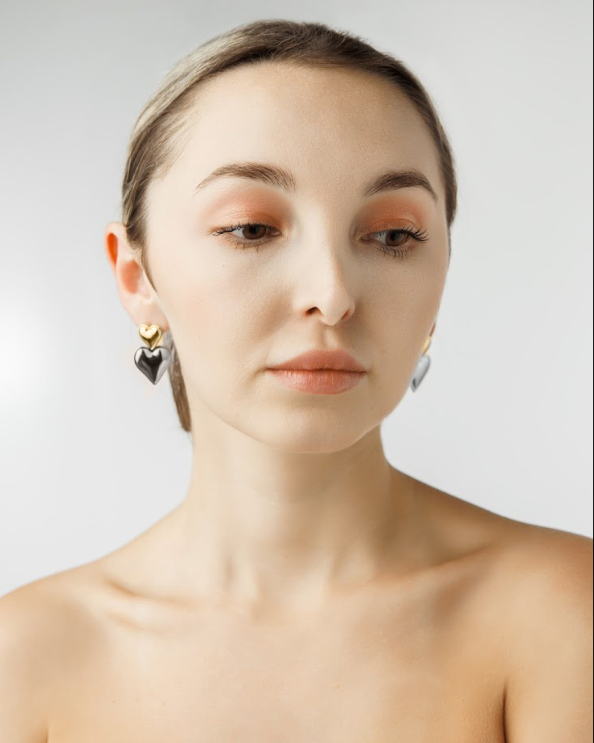 Front view of model wearing Sadie Earrings featuring gold and silver heart drops.