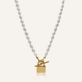 Lily Necklace flatlay showing freshwater pearls and gold padlock pendant with toggle closure.