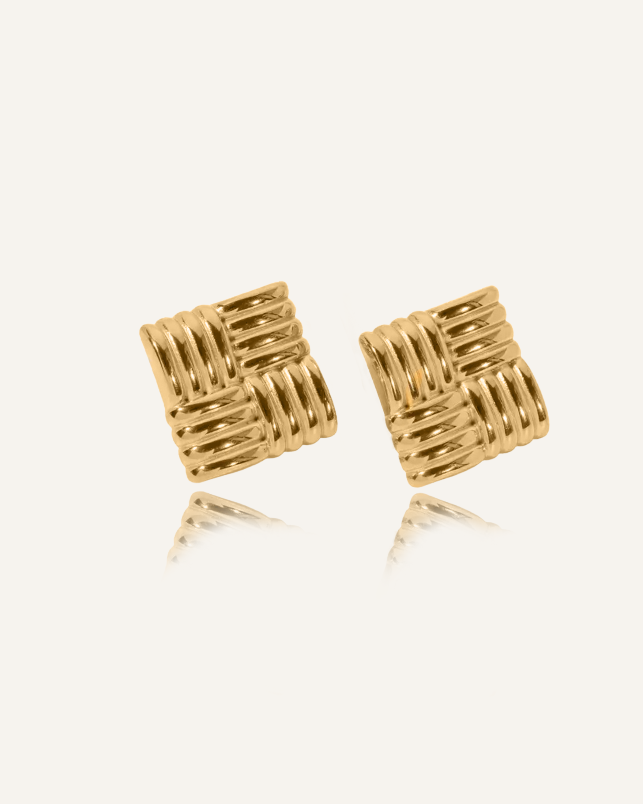 Asha Earrings in gold shown in flatlay, featuring tropical woven texture and drop design.