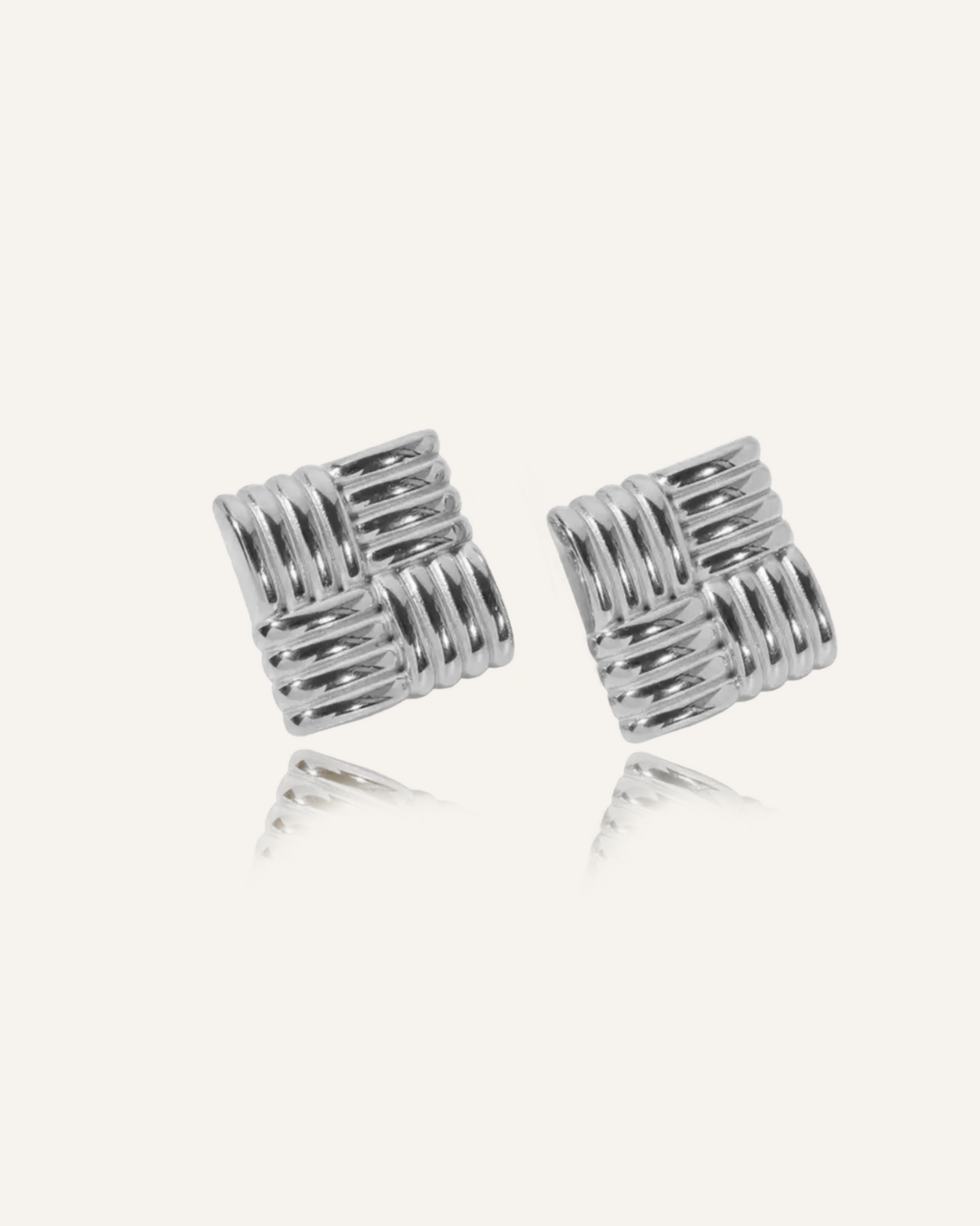 Flatlay of Asha Earrings in silver, showing woven texture and elegant round drop design.