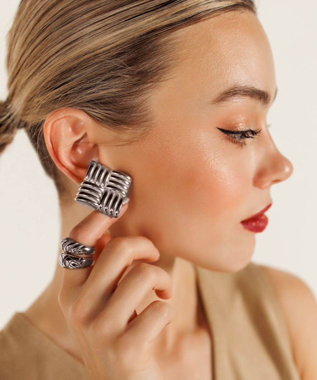 Close-up of model wearing Asha Earrings in silver, highlighting their tropical woven detail.