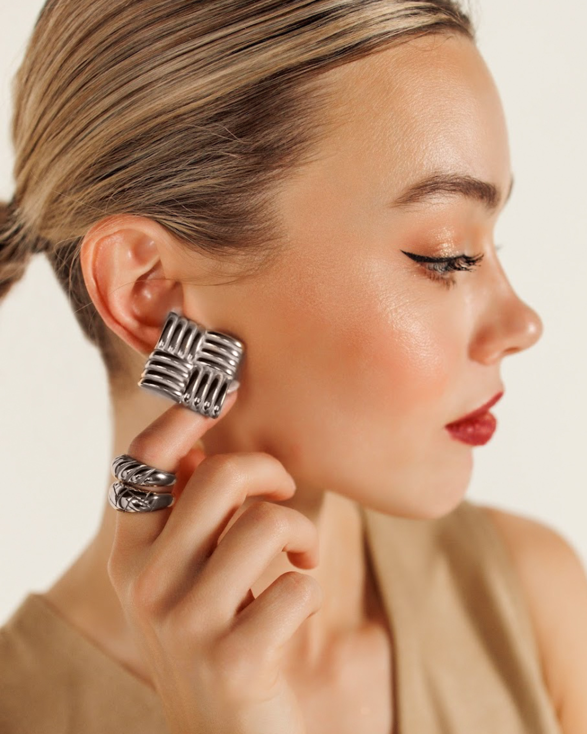 Close-up of model wearing Asha Earrings in silver, highlighting their tropical woven detail.