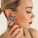 Close-up of model wearing Asha Earrings in silver, highlighting their tropical woven detail.