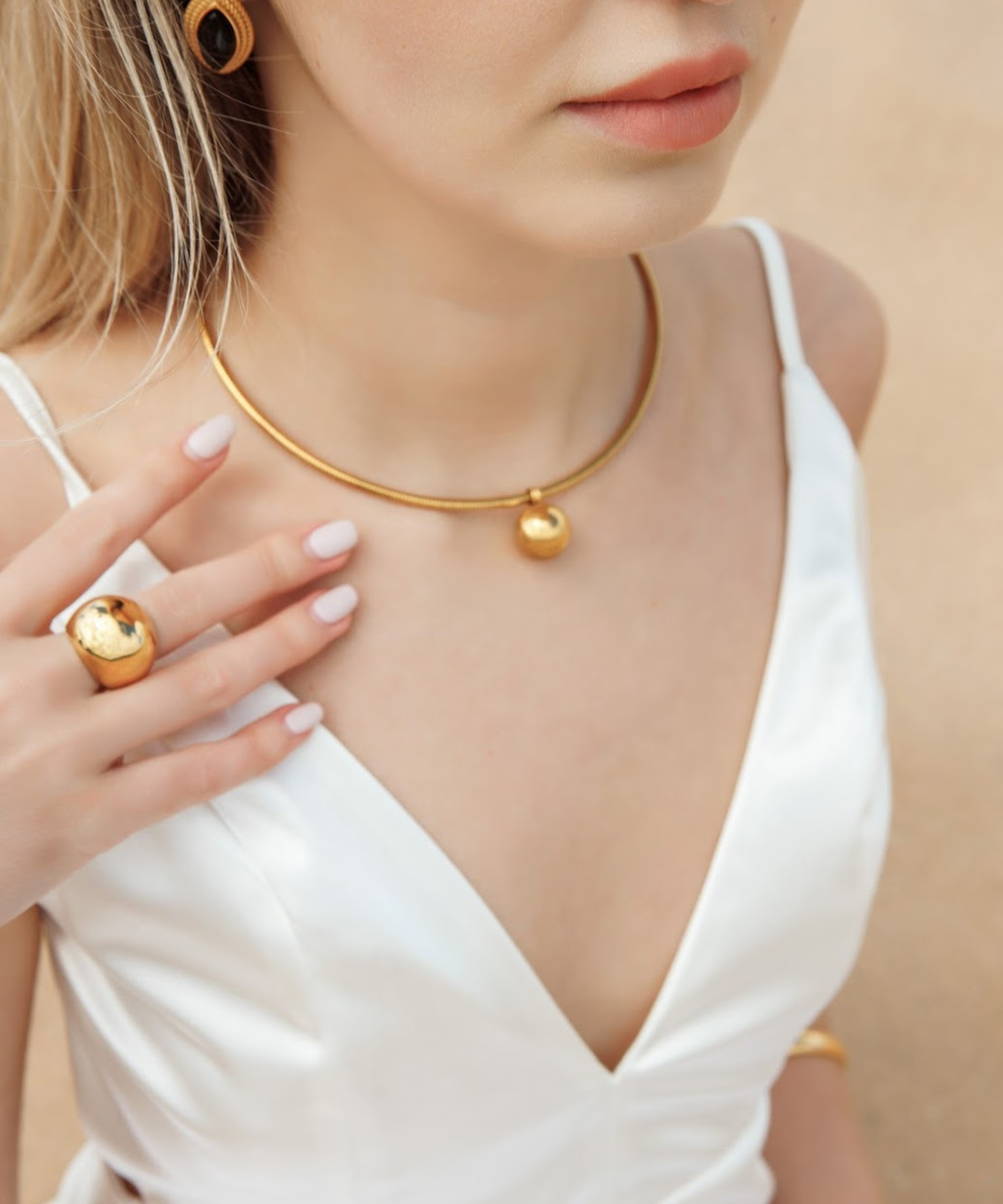 Close-up view of Casie Necklace's 18k gold-coated dome pendant.