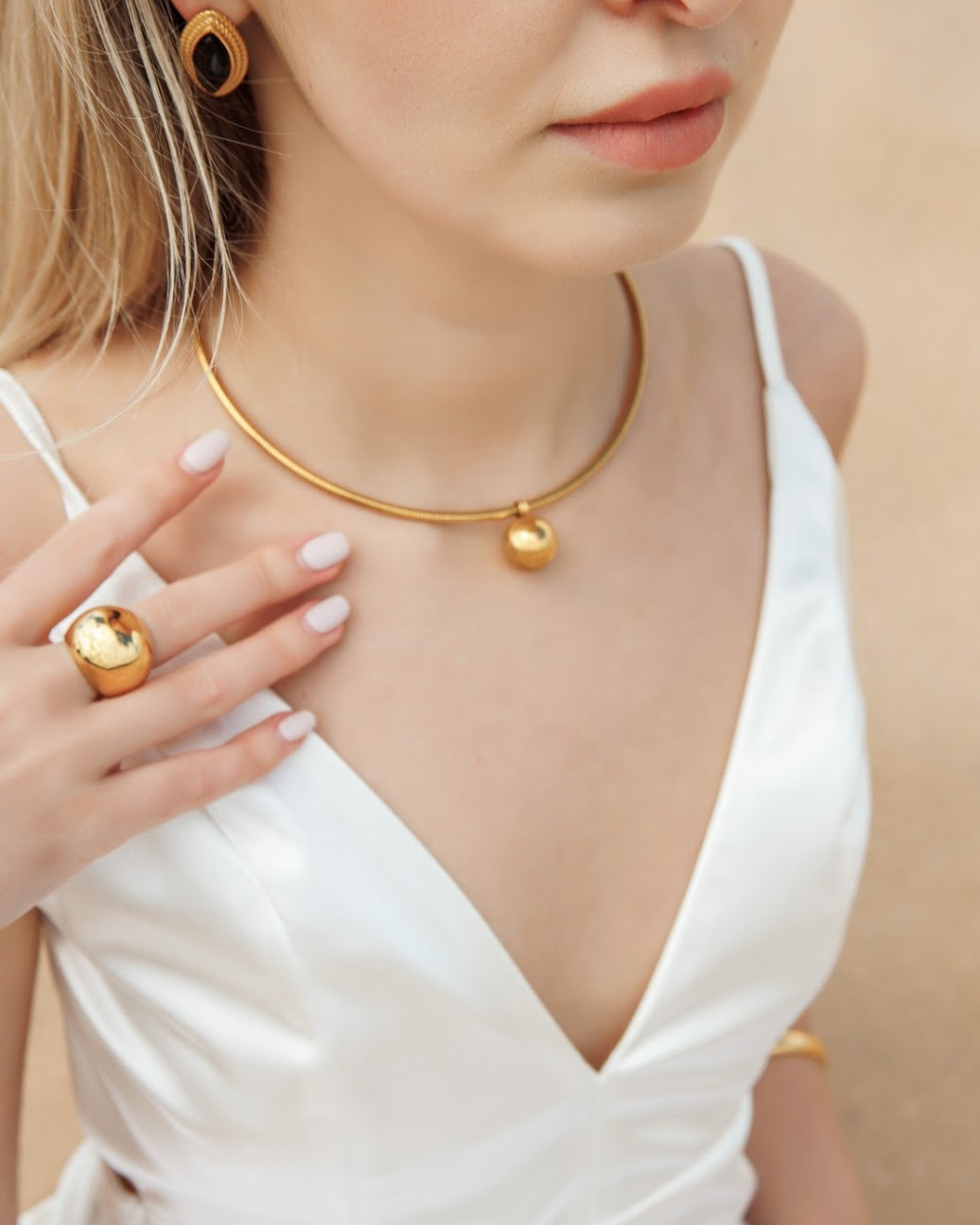 Close-up view of Casie Necklace's 18k gold-coated dome pendant.