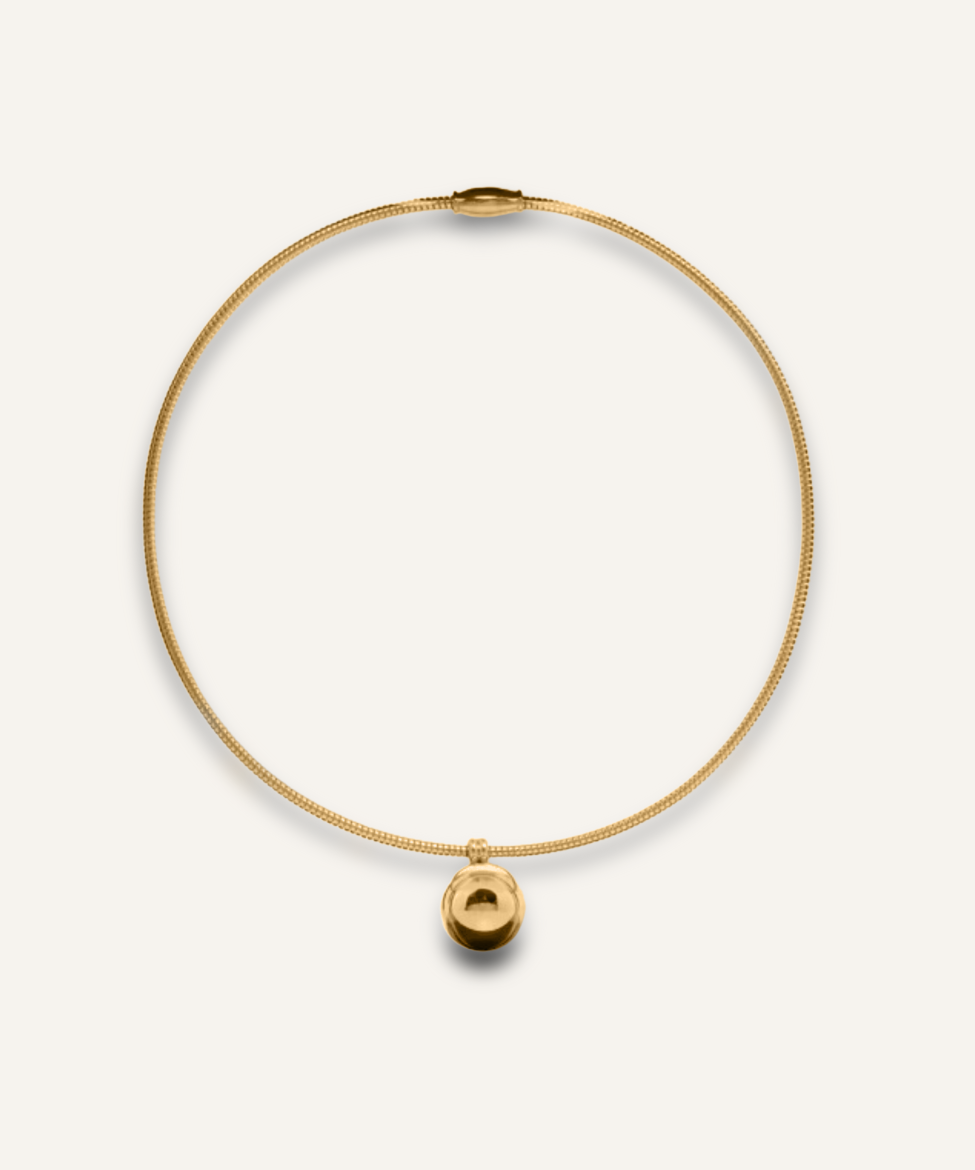 Casie Necklace in gold with bold dome pendant on snake chain, laid flat on white background.