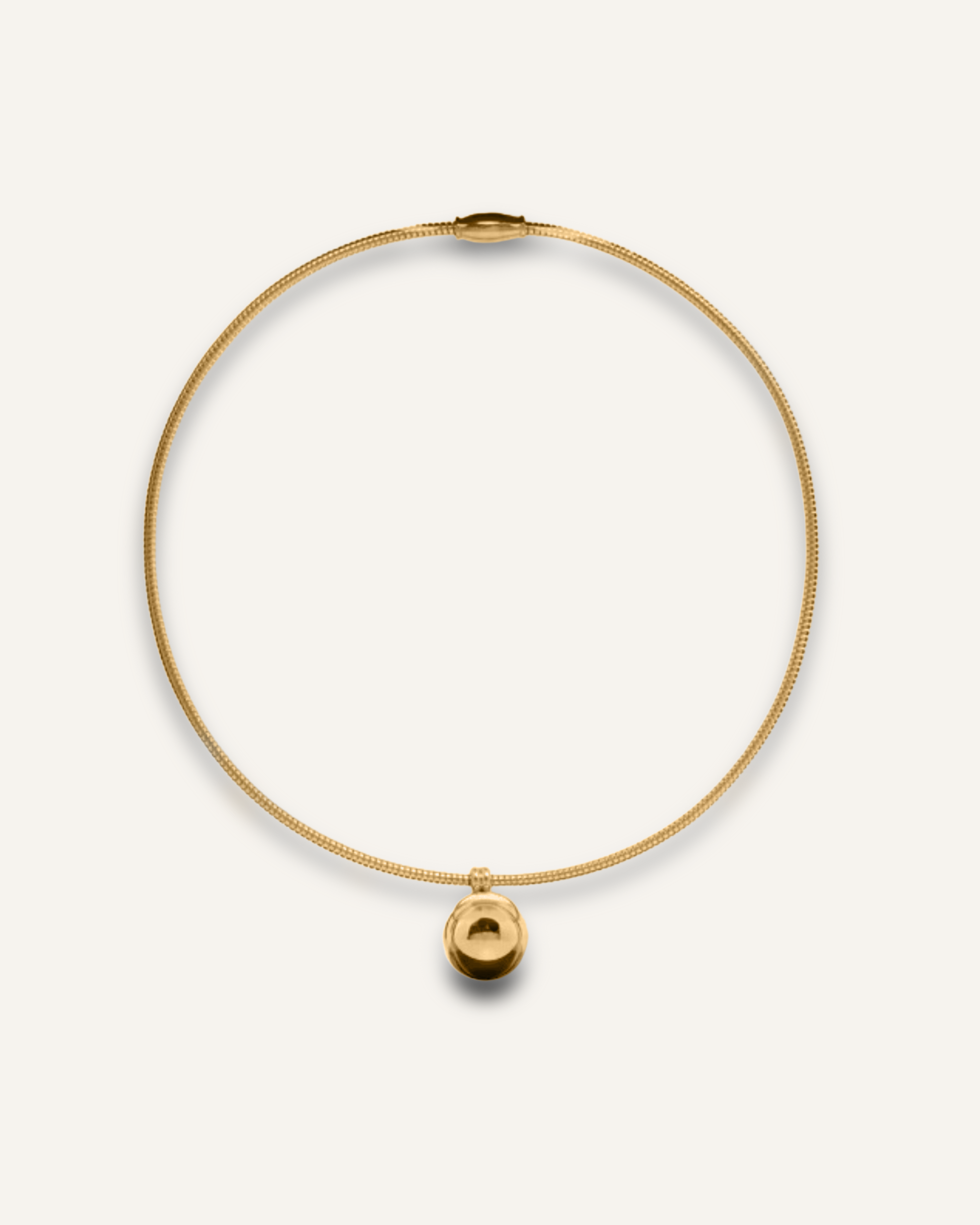 Casie Necklace in gold with bold dome pendant on snake chain, laid flat on white background.
