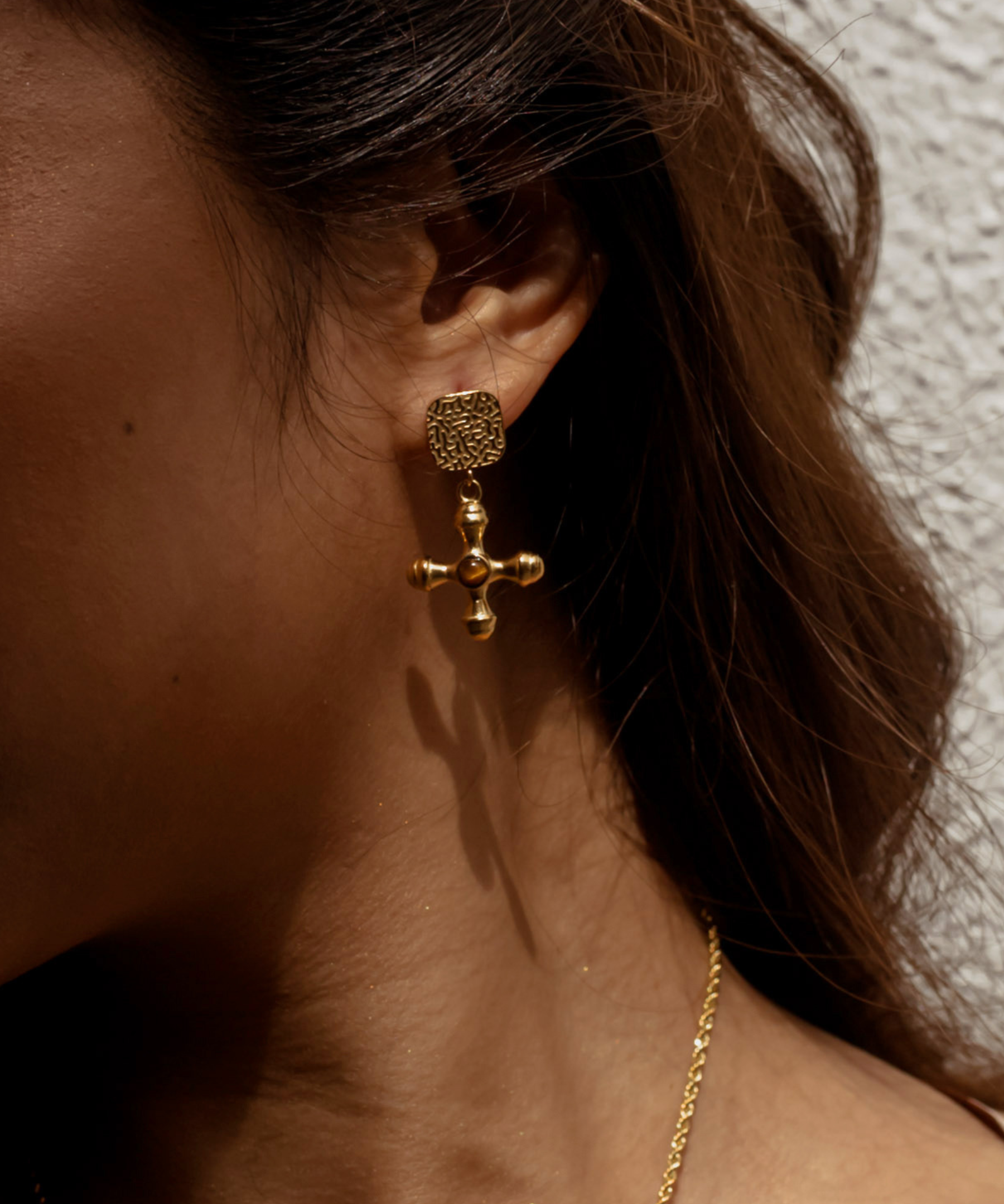 Woman wearing Chiara Earrings with gold and Tiger Eye stone drop.
