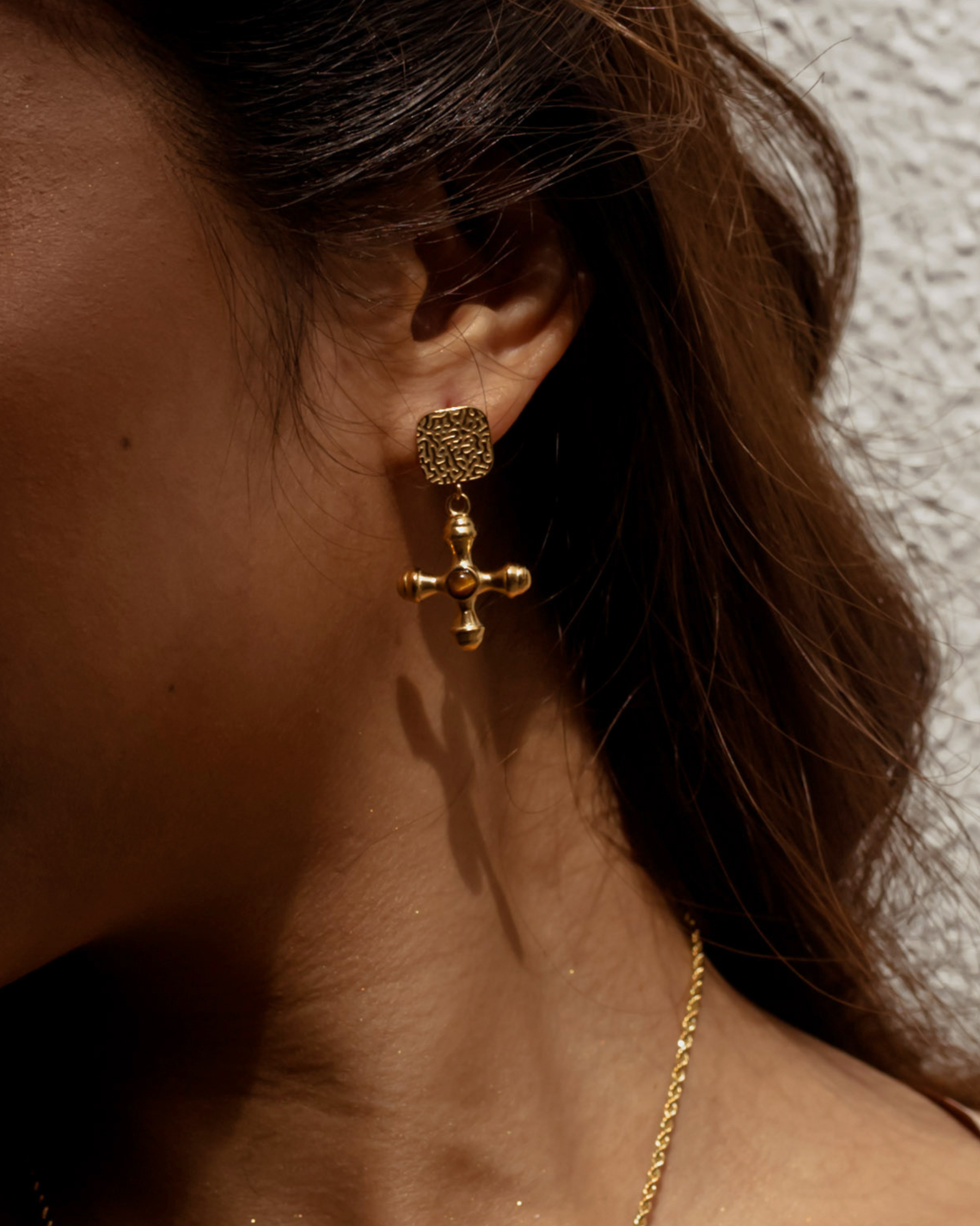 Woman wearing Chiara Earrings with gold and Tiger Eye stone drop.