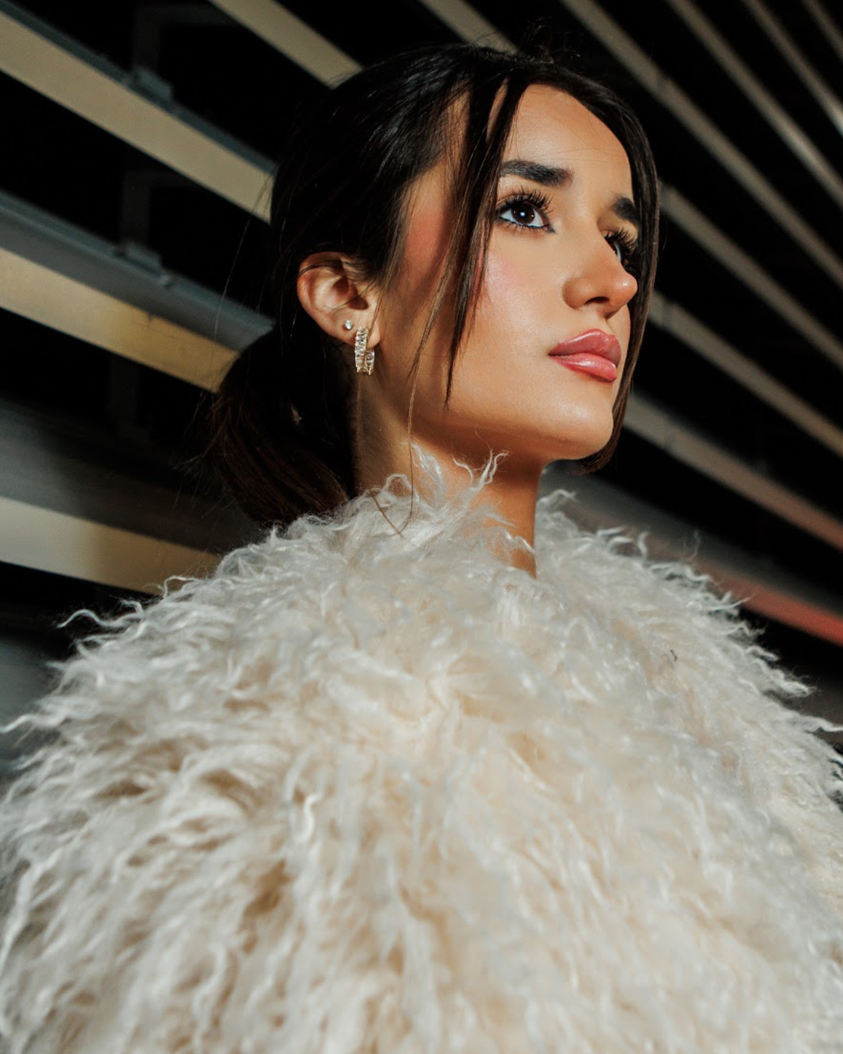 Claire gold earrings worn on model showcasing bold geometric huggie hoop design with cubic zirconia.