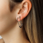 Model wearing silver Gil Earrings styled as a safety pin, showing off their bold and unconventional design.