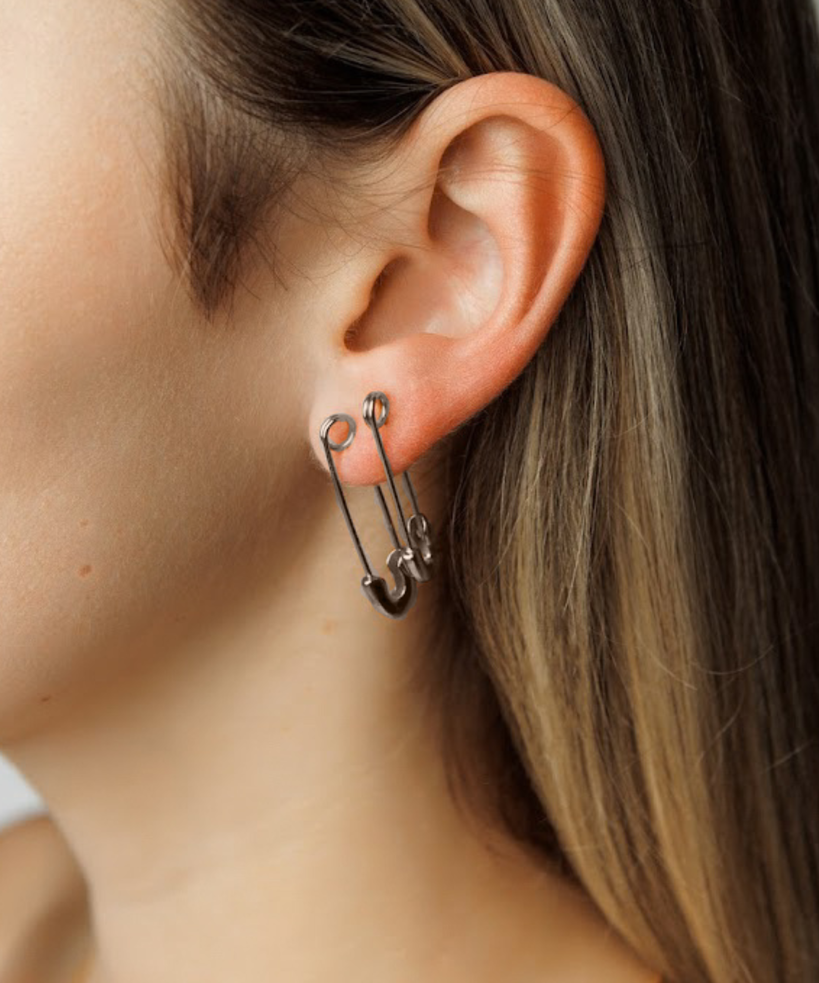 Model wearing silver Gil Earrings styled as a safety pin, showing off their bold and unconventional design.