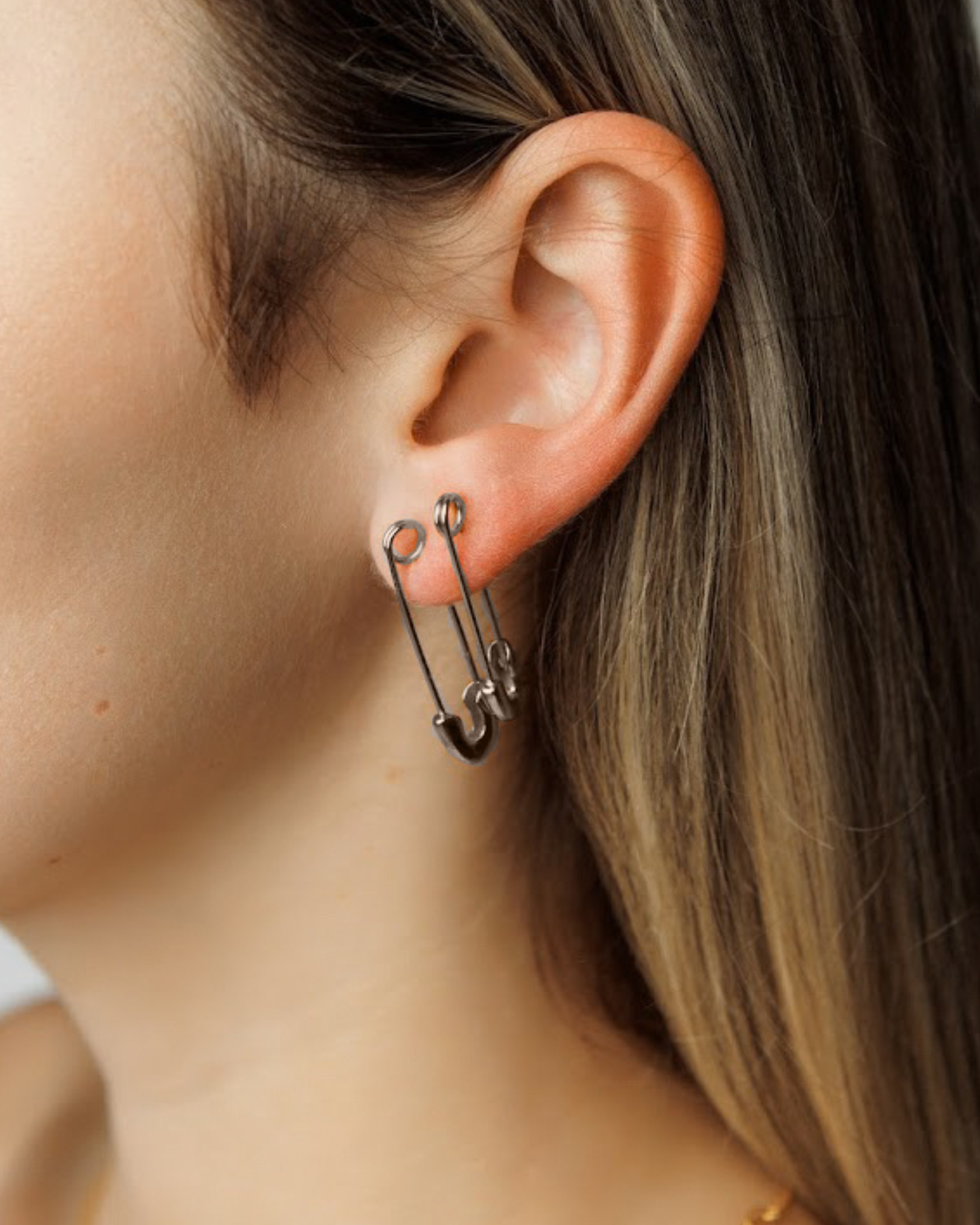 Model wearing silver Gil Earrings styled as a safety pin, showing off their bold and unconventional design.