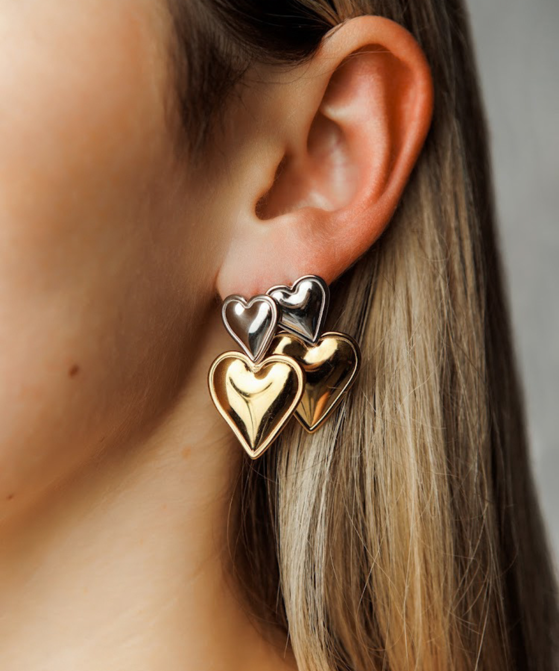 Close-up view of Giselle Earrings highlighting stacked heart detail in gold and silver.