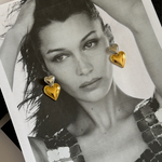 Front view of model wearing gold and silver Giselle heart drop earrings.