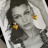 Front view of model wearing gold and silver Giselle heart drop earrings.