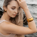 Woman wearing the Indie Gold Cuff with a light brown top, showcasing its bold yet minimal design.