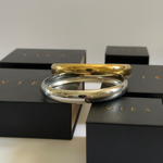 Silver and gold Indie Cuffs stacked together atop VIEA Jewelry packaging.