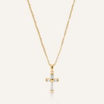 Flatlay of Iris Necklace featuring gold chain and cross pendant with zirconia stones.