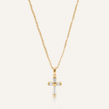 Flatlay of Iris Necklace featuring gold chain and cross pendant with zirconia stones.