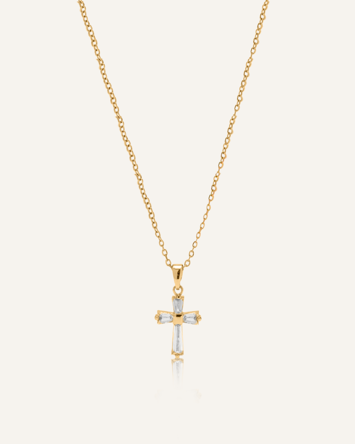 Flatlay of Iris Necklace featuring gold chain and cross pendant with zirconia stones.
