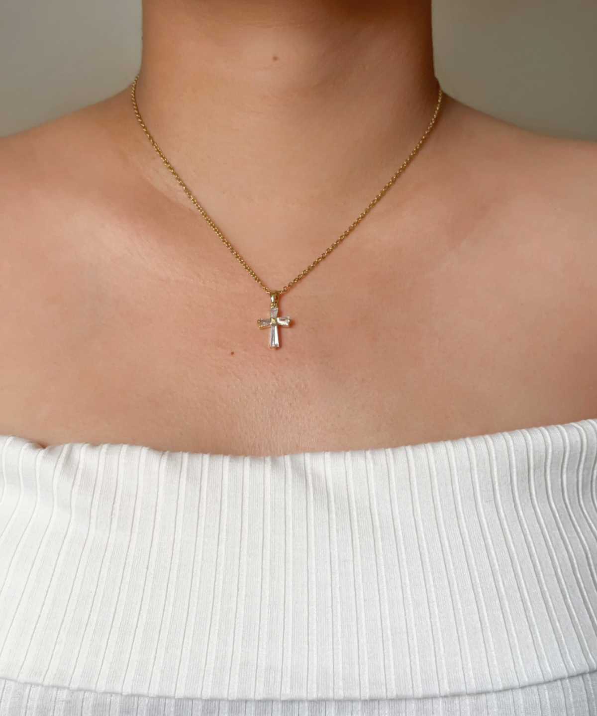 Model wearing the Iris Necklace, showing the sparkling cross pendant on a gold chain.