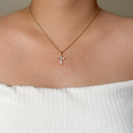 Model wearing the Iris Necklace, showing the sparkling cross pendant on a gold chain.