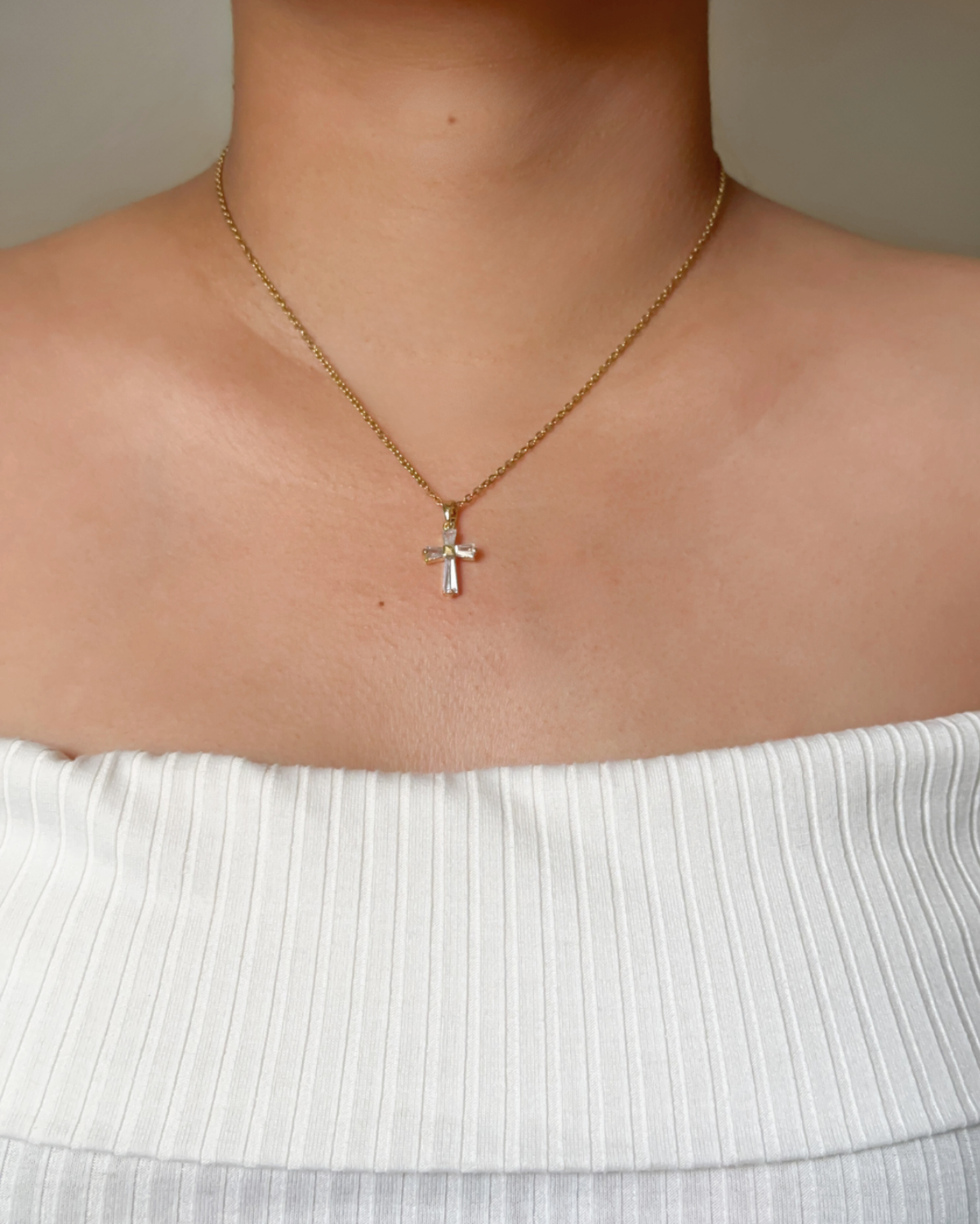 Model wearing the Iris Necklace, showing the sparkling cross pendant on a gold chain.