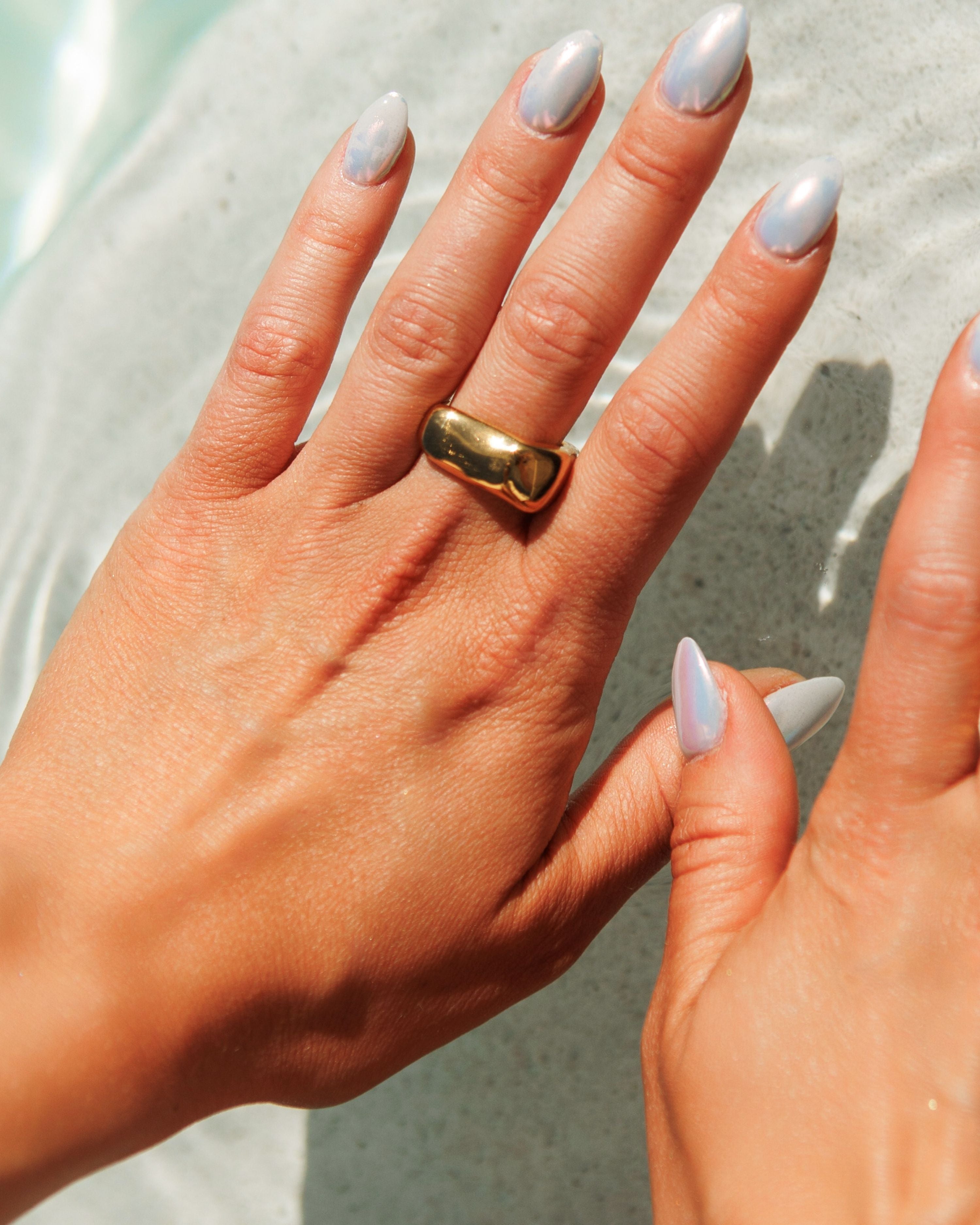 Close-up of gold Kyma Ring with irregular square design on finger.