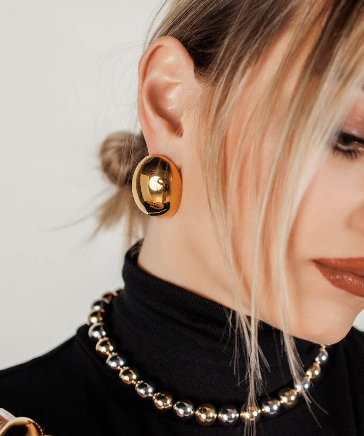 Close-up view of model wearing gold Leigh Earrings highlighting dome shape.