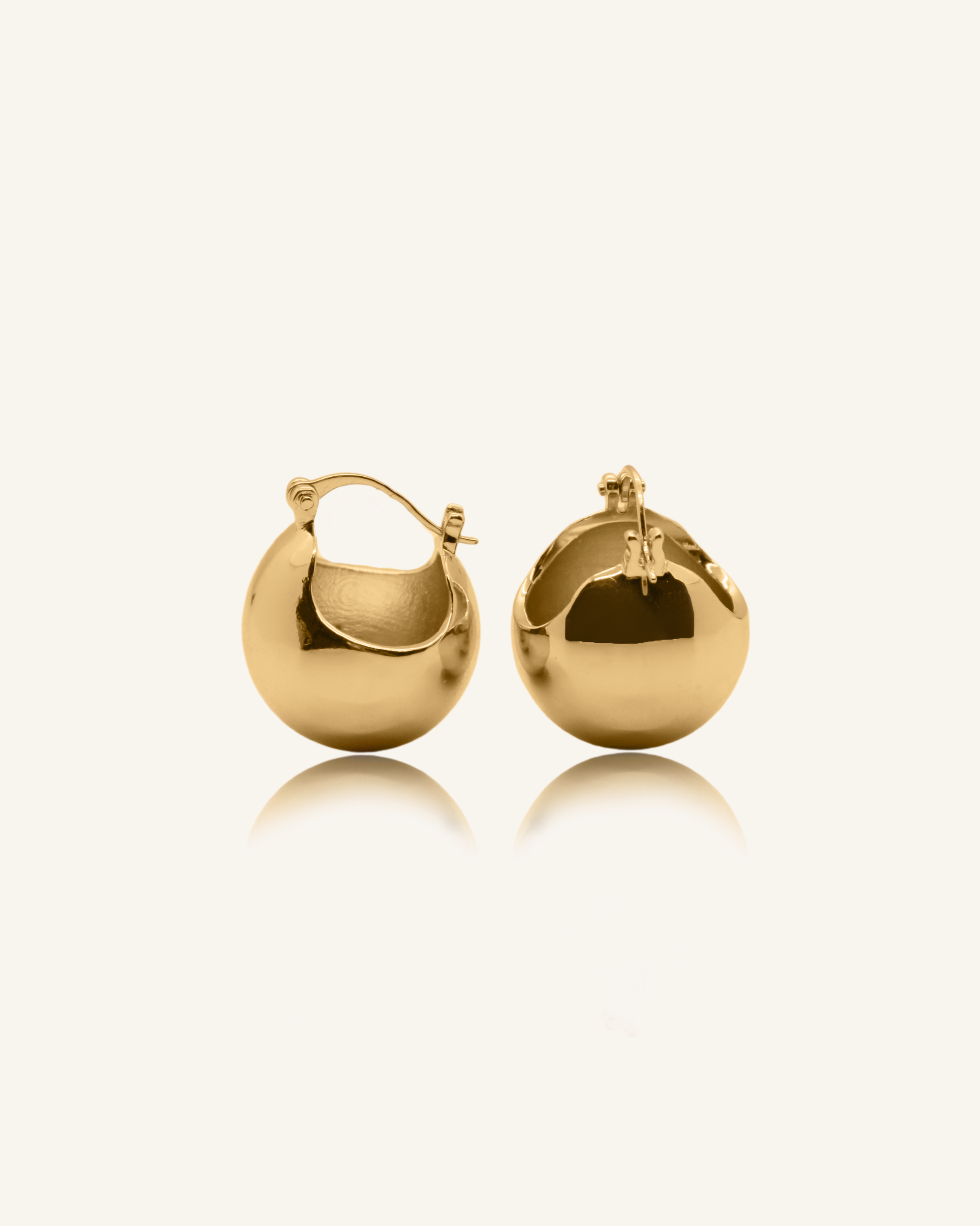 Flatlay of Maeve Earrings in gold featuring a bold dome shape and polished finish.