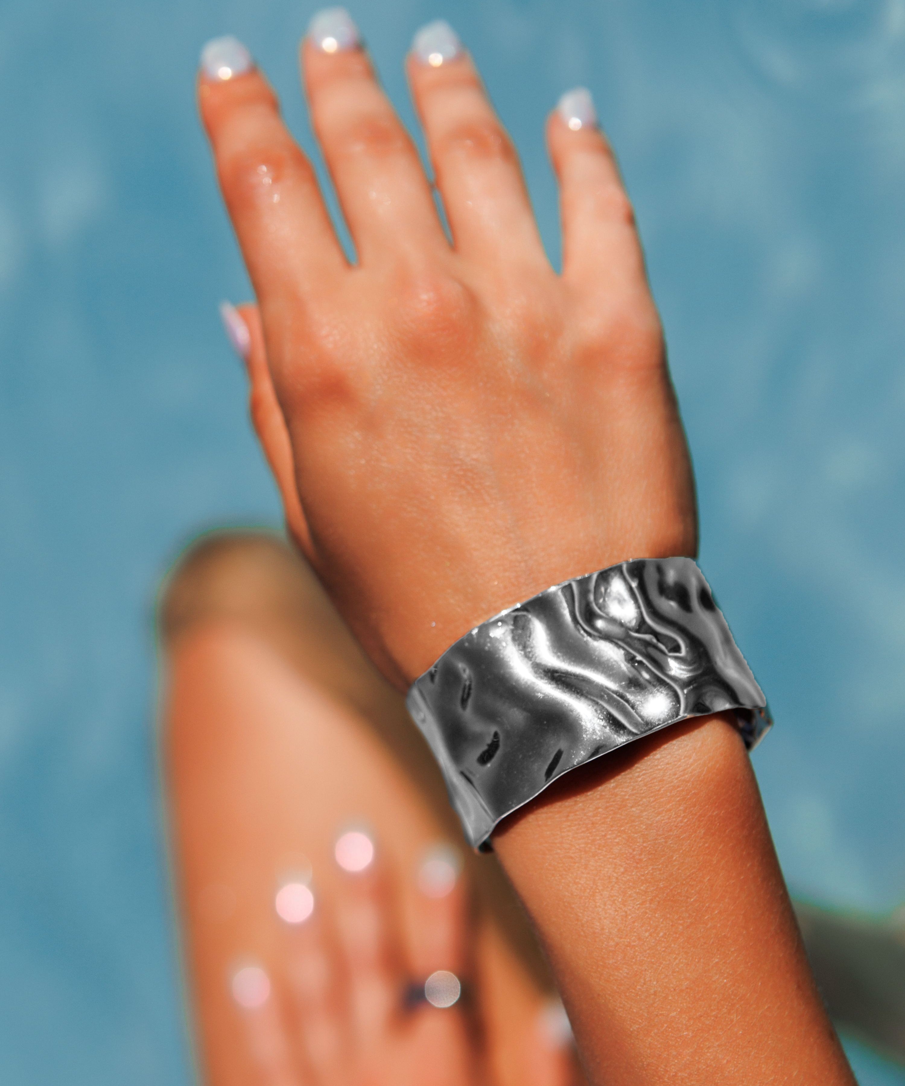  Close-up of the molten texture of Mara Cuff in silver on wrist.