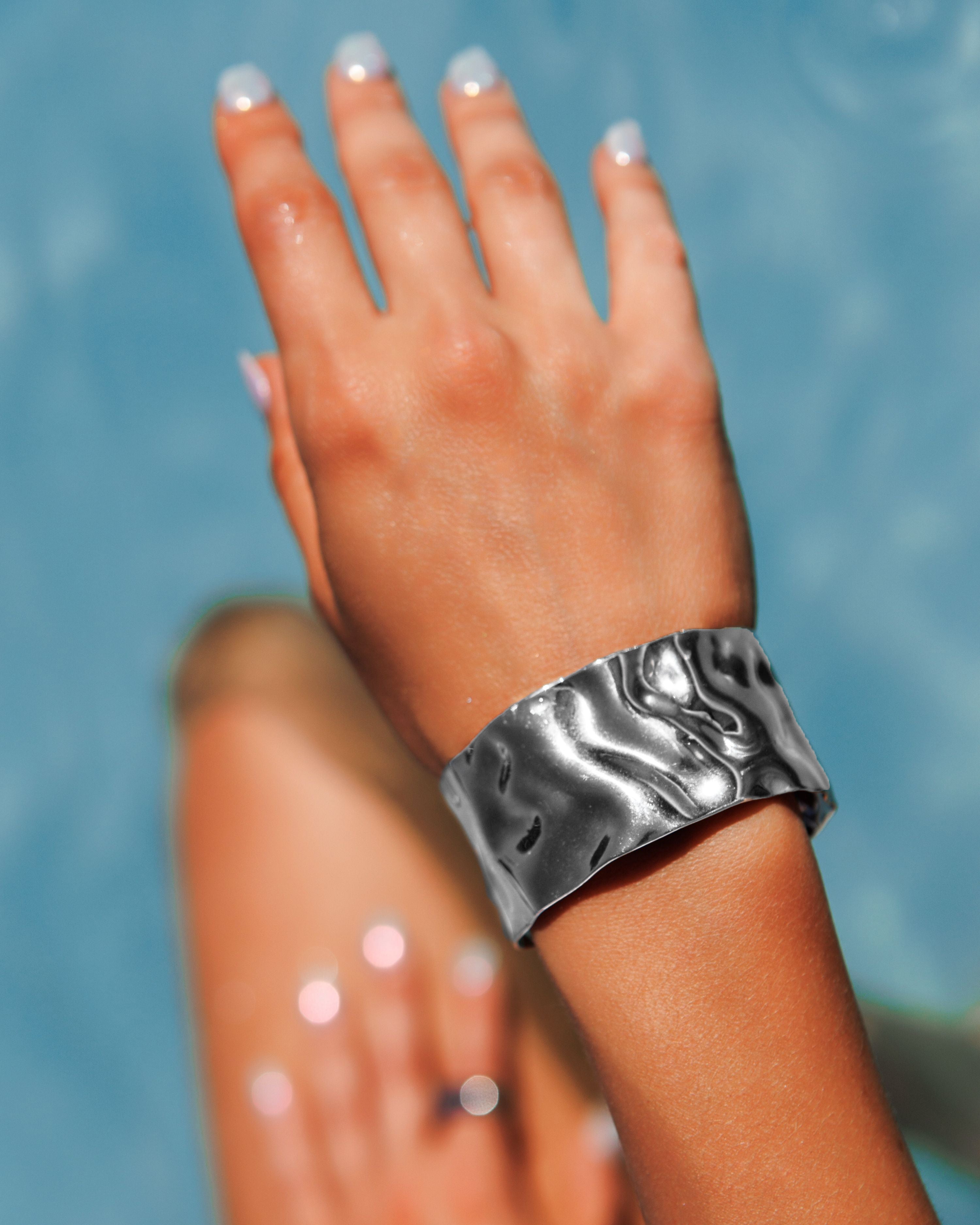  Close-up of the molten texture of Mara Cuff in silver on wrist.