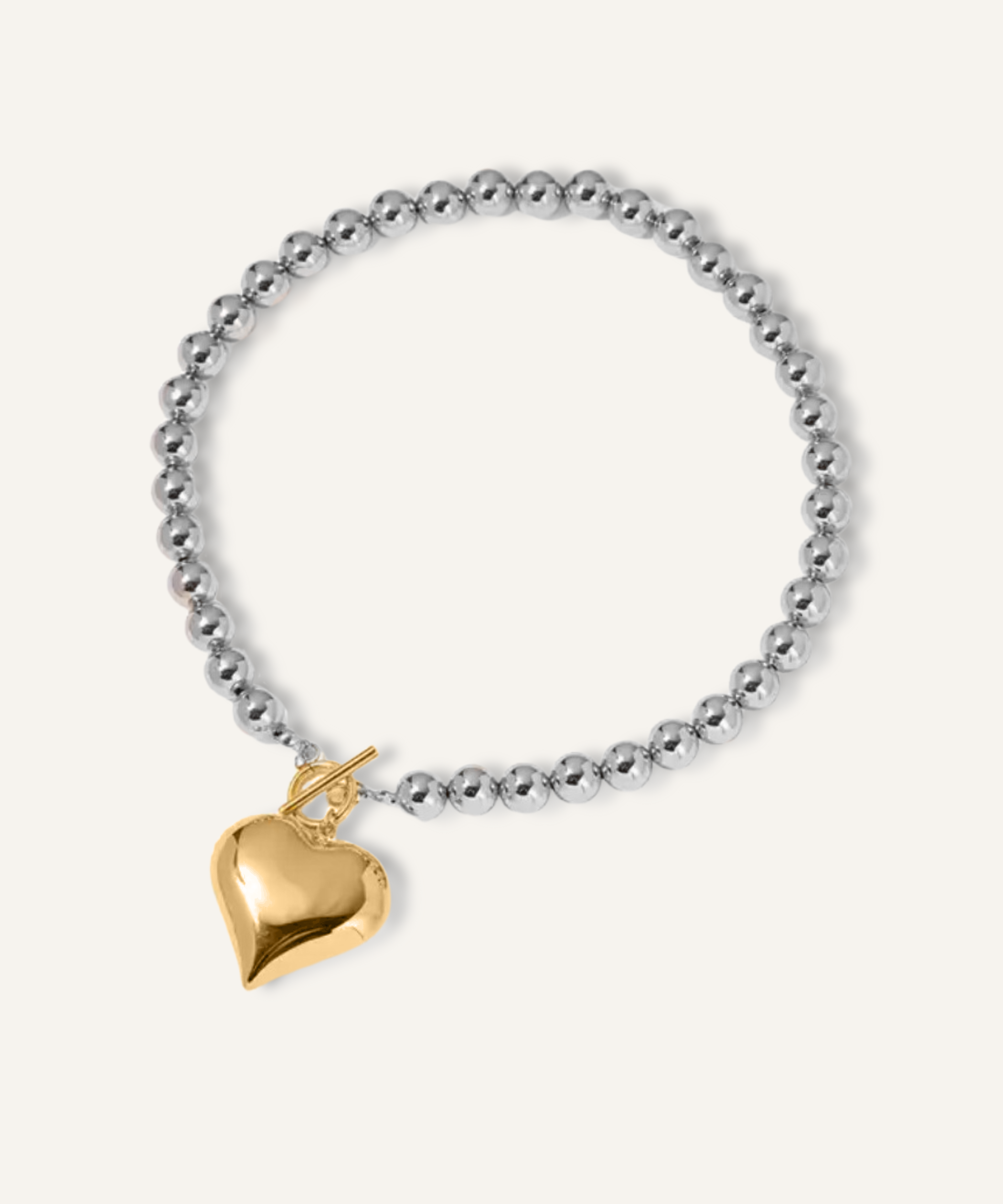 Flatlay of Margaux Necklace featuring a gold heart-shaped pendant and silver beaded chain.