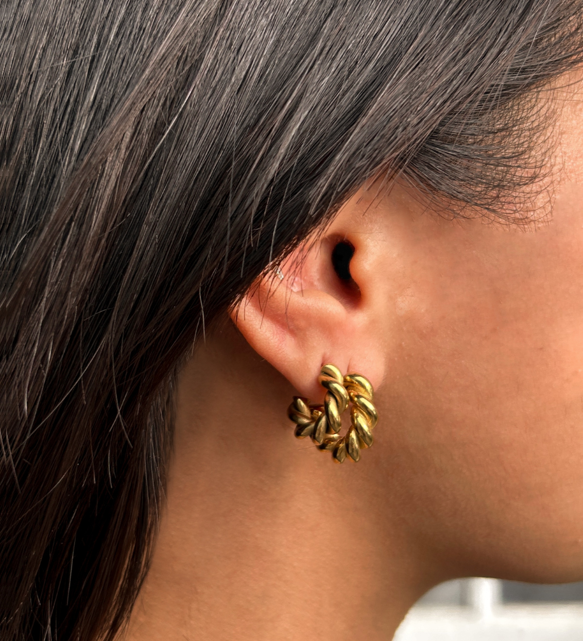 Close-up shot of model wearing Mini Celeste Earrings, highlighting the elegant vintage twist detail.