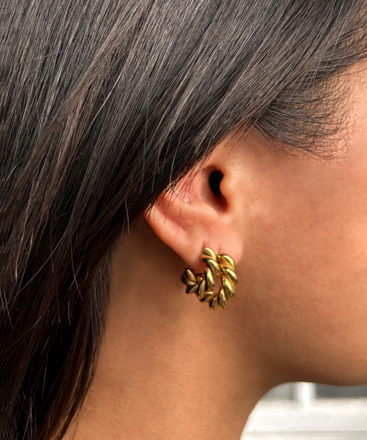 Close-up shot of model wearing Mini Celeste Earrings, highlighting the elegant vintage twist detail.