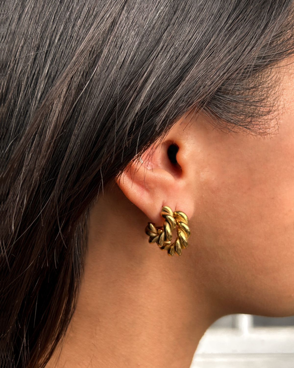 Close-up shot of model wearing Mini Celeste Earrings, highlighting the elegant vintage twist detail.