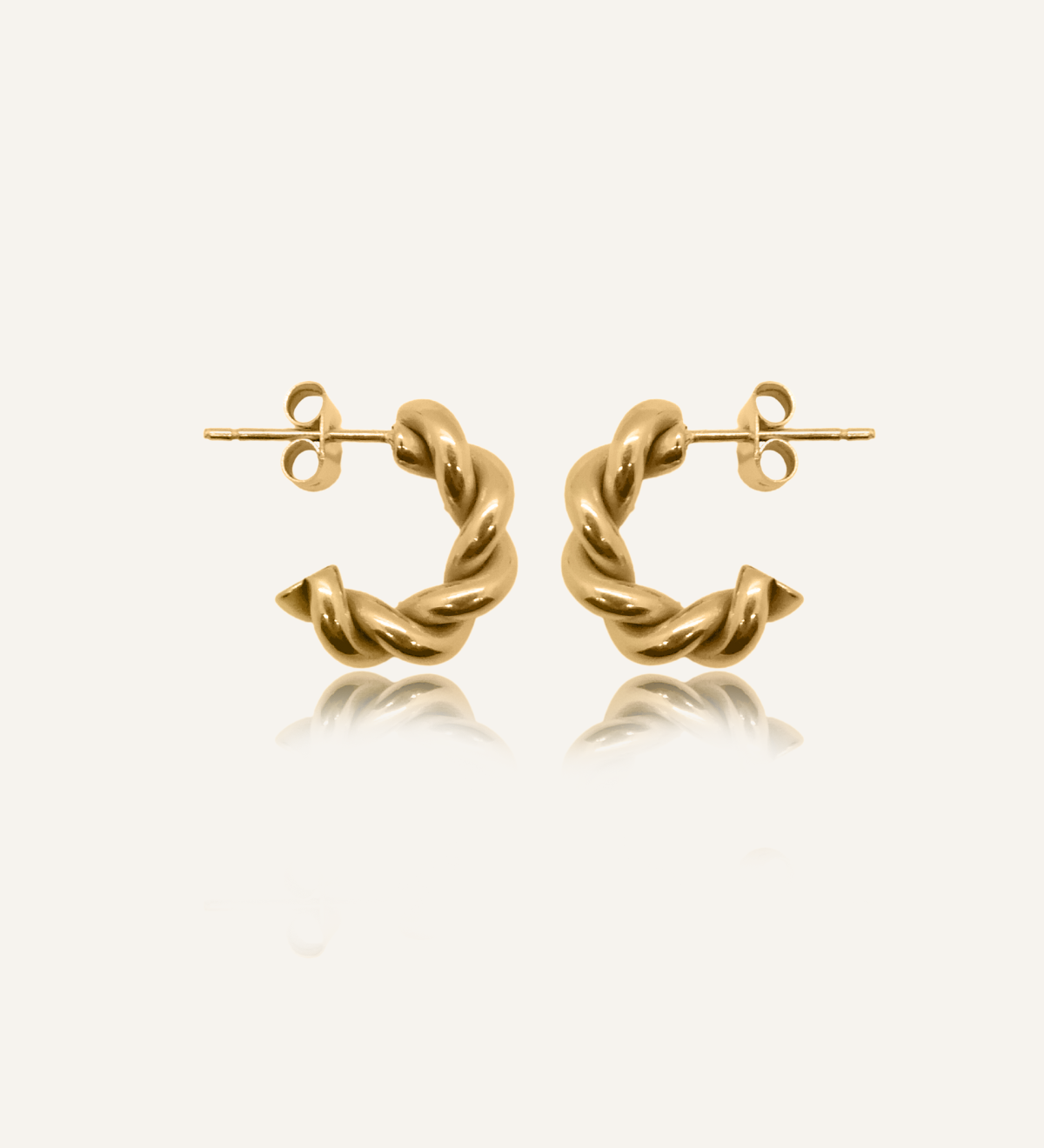 Flatlay of Mini Celeste Earrings in 18k gold, showcasing their twisted rope design and semi-hoop shape.