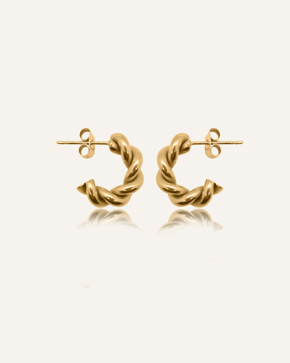 Flatlay of Mini Celeste Earrings in 18k gold, showcasing their twisted rope design and semi-hoop shape.