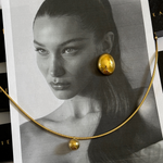 Mona Gold Earrings styled elegantly with hair tucked, highlighting statement design.