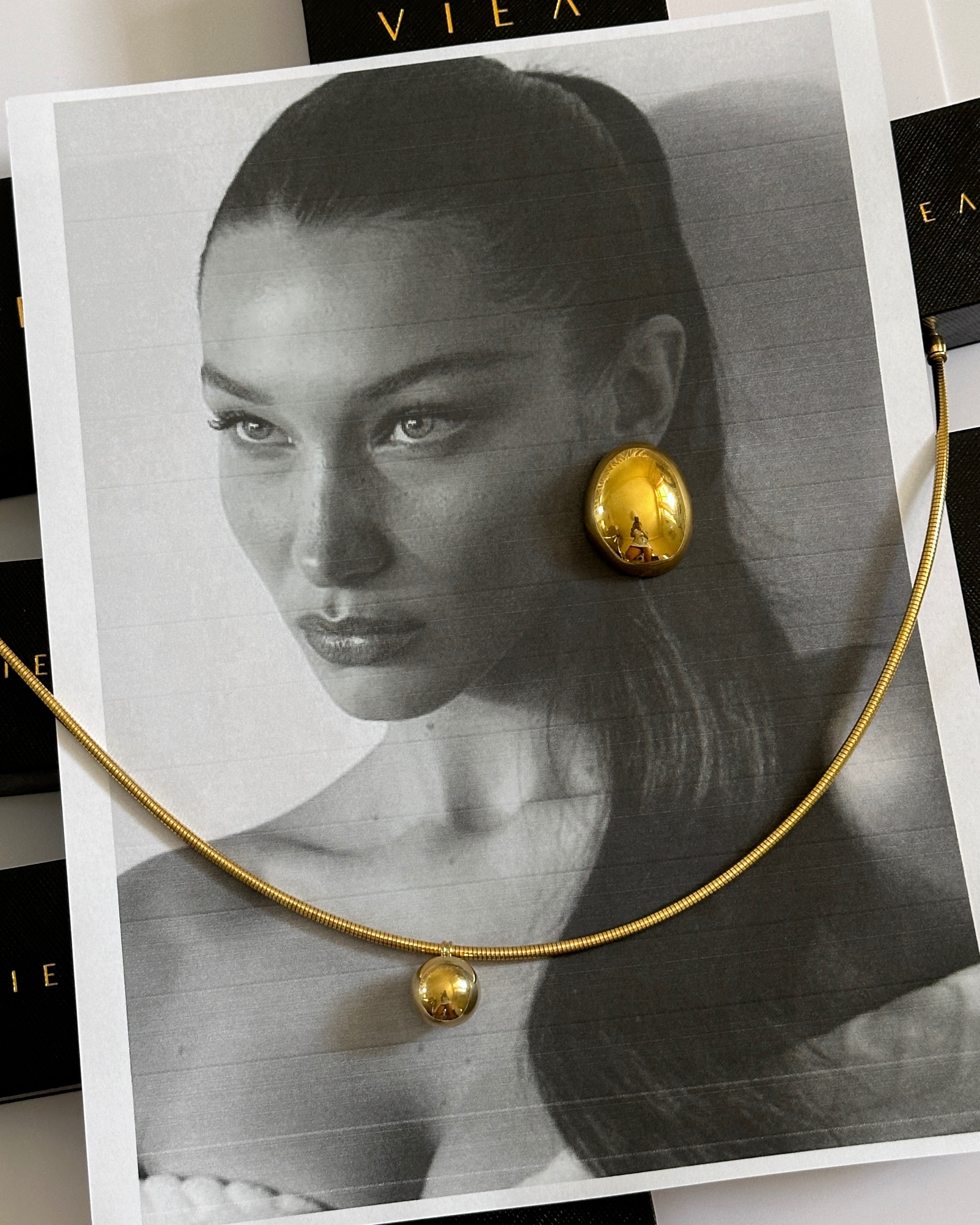 Mona Gold Earrings styled elegantly with hair tucked, highlighting statement design.