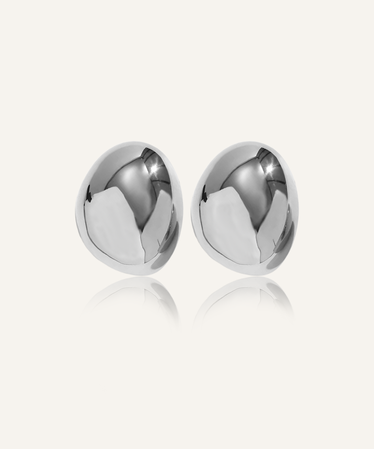 Mona Earrings in silver with bold oval dome design, laid flat on white surface.